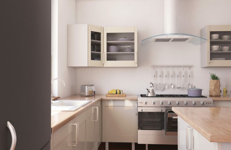 Cuisine moderne avec des meubles de rangement en beige et un plan de travail en bois. Équipée d'une cuisinière en acier inoxydable, d'une hotte moderne, et d'éléments de cuisine organisés sur le mur. Exemple d'aménagement de cuisine par Bricomarché Cosne.